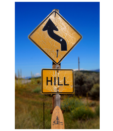 longboard resting against a hill street sign