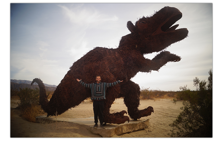 standing in front of a huge metal monster sculpture