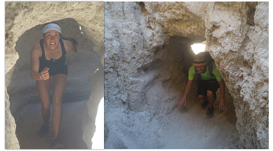 hikers crouching through small mud cave arches