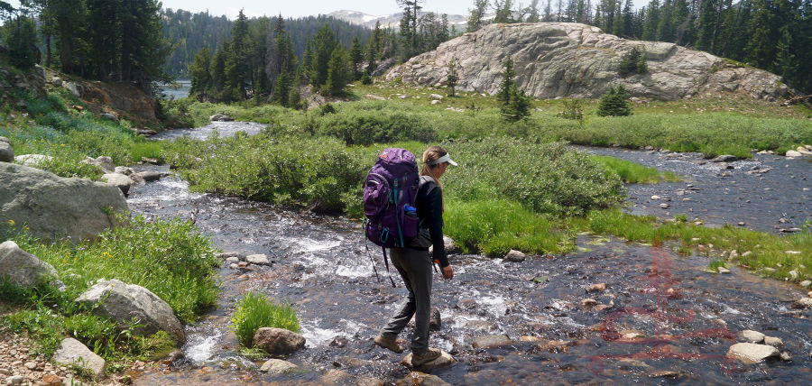 backpacker crossing a stream