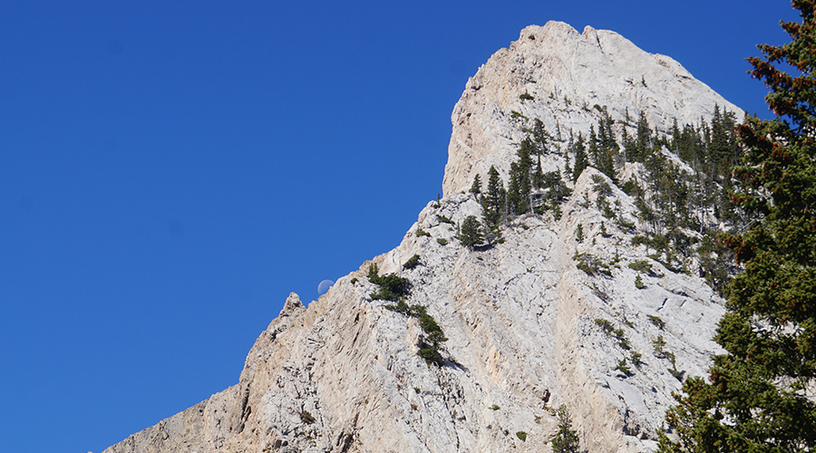 moon peaking out from granite mountains