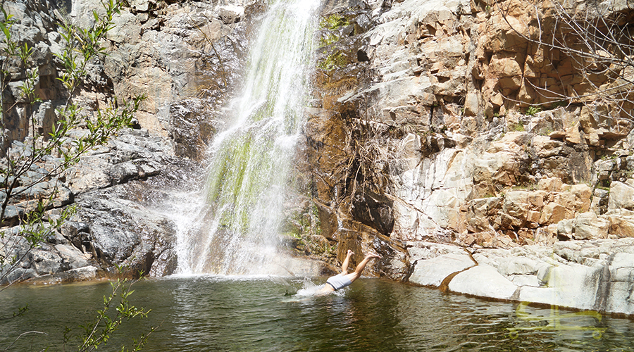Shane jumping into the pool of water at the base of the large waterfall