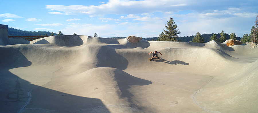 surfing the main bowl area on a longboard at the mammoth skatepark