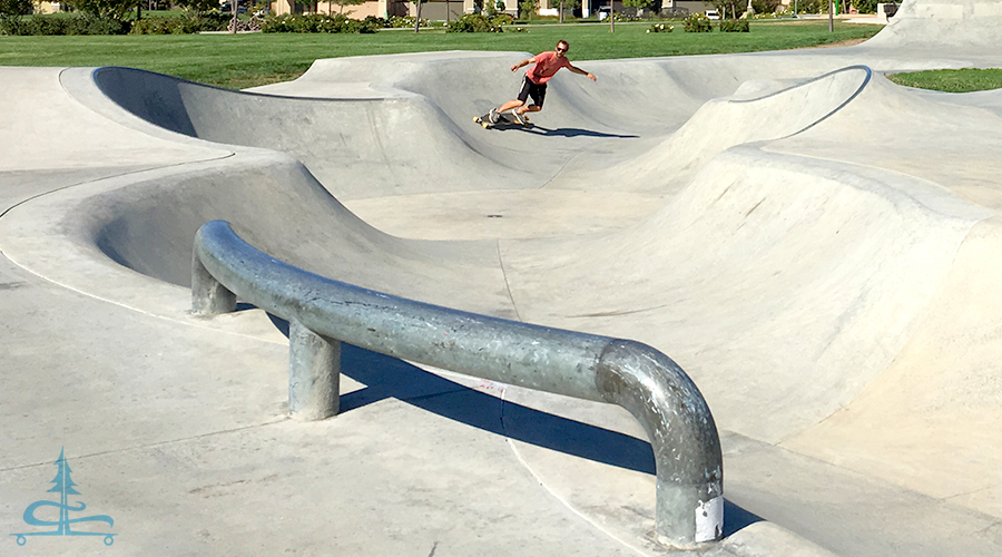 cruising a snake run while longboarding in a skatepark