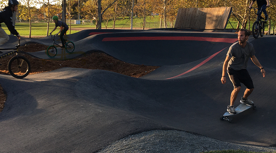 bikes and longboarder at temecula pump track