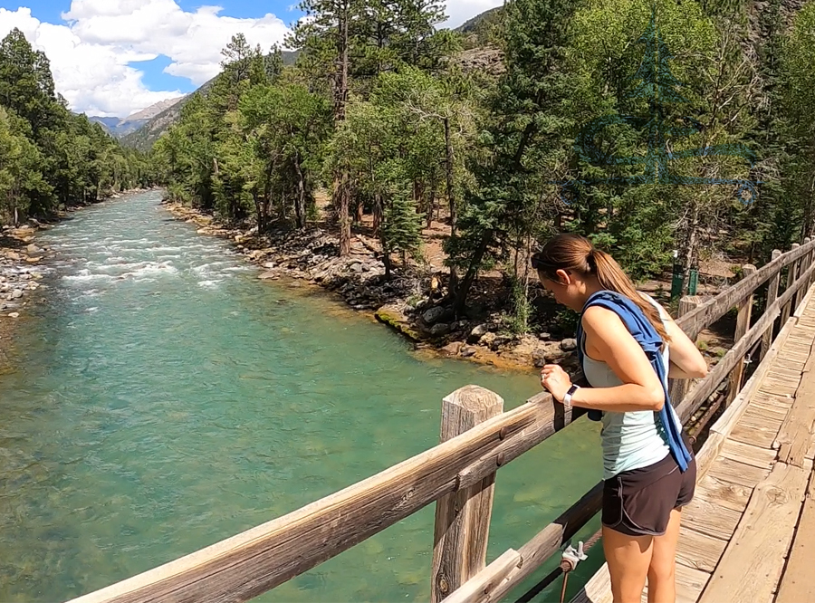 hiking purgatory trail across the pedestrian bridge over the glacial blue animas river