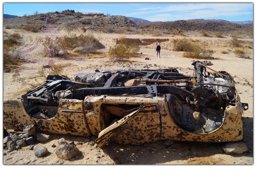 rusty shot up car in the desert